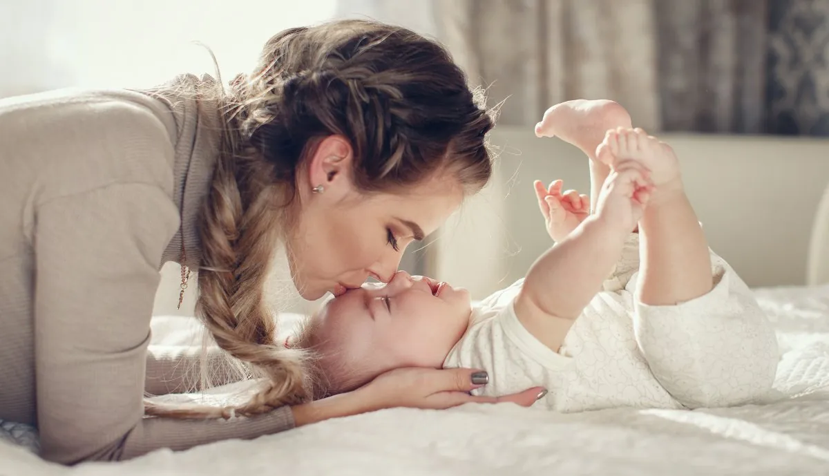 Mutter küsst ihr lachendes Baby liebevoll